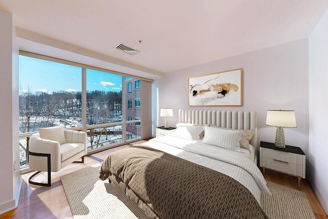 bedroom featuring light wood-type flooring, visible vents, and expansive windows