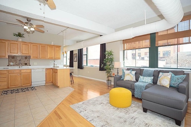 living area featuring light wood finished floors, baseboards, ceiling fan, beamed ceiling, and a textured ceiling