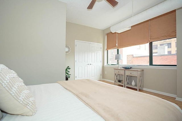 bedroom featuring a ceiling fan, wood finished floors, baseboards, and a closet