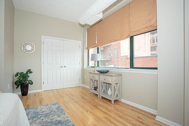 bedroom with light wood-style floors, baseboards, and a closet