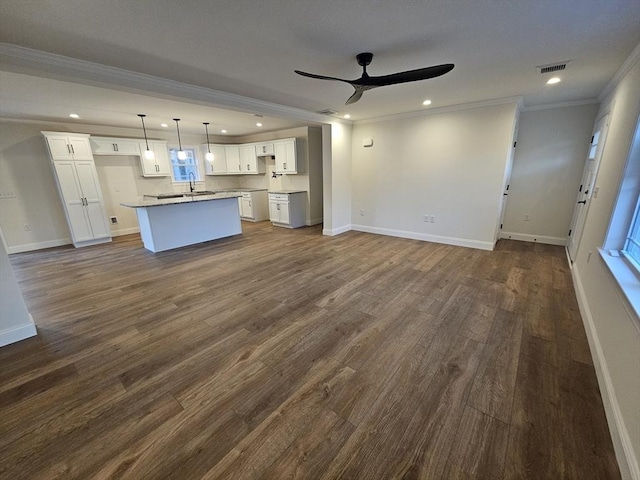 kitchen with white cabinetry, pendant lighting, a center island with sink, and crown molding