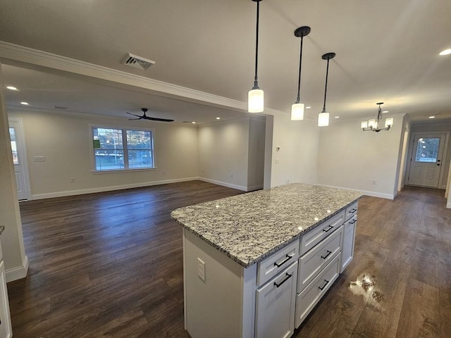 kitchen with decorative light fixtures, a center island, light stone countertops, ceiling fan with notable chandelier, and white cabinets