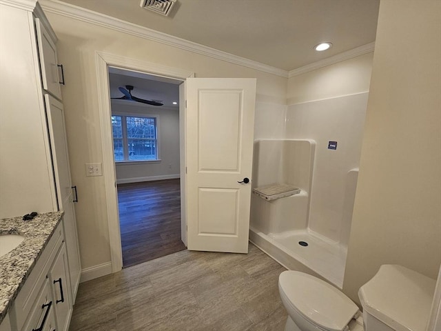 bathroom featuring walk in shower, toilet, vanity, ornamental molding, and ceiling fan