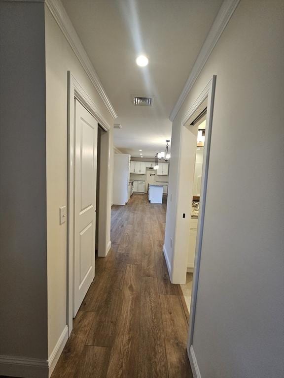 hall with ornamental molding, dark hardwood / wood-style floors, and a chandelier