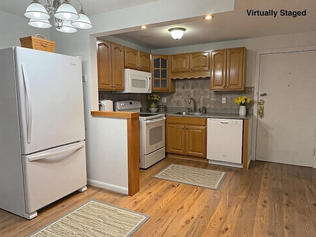 kitchen featuring decorative backsplash, white appliances, wood finished floors, and a sink