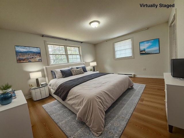 bedroom with baseboards, multiple windows, and wood finished floors