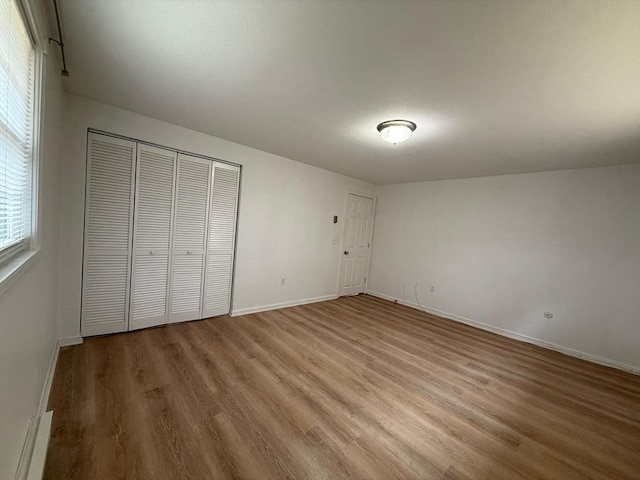 unfurnished bedroom featuring a closet, baseboards, and wood finished floors