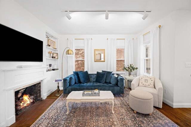 living room with track lighting and a fireplace with flush hearth