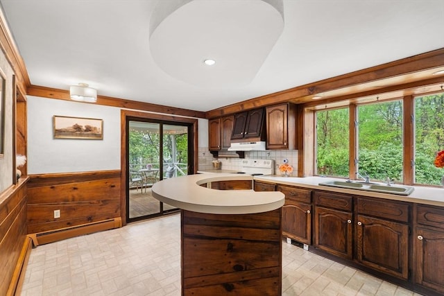 kitchen with a sink, a baseboard radiator, electric range oven, light countertops, and brick patterned floors