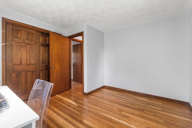 unfurnished office featuring baseboards and light wood finished floors