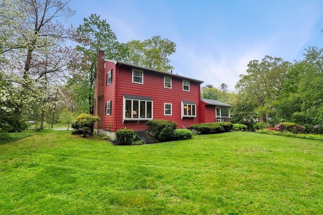 rear view of property with a chimney and a yard
