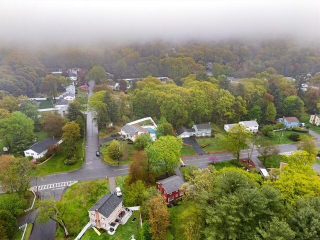 aerial view of property's location with nearby suburban area and a heavily wooded area