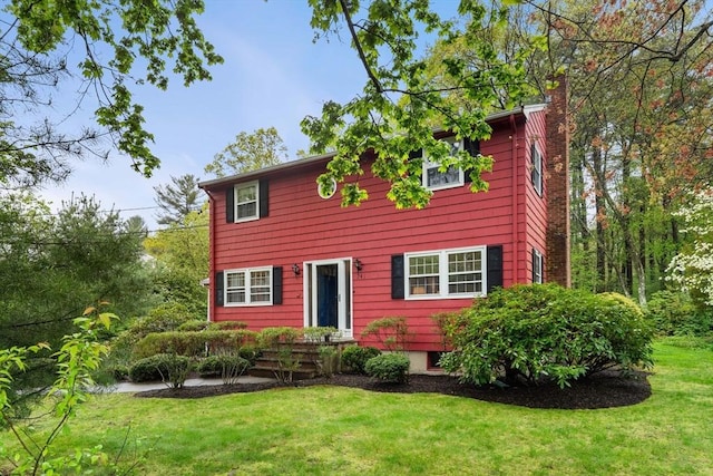 colonial inspired home featuring a chimney and a front yard