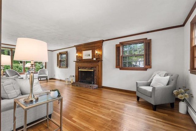 living room featuring ornamental molding, light wood-type flooring, a brick fireplace, and baseboards
