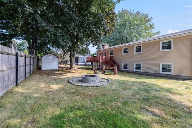 view of yard with a storage unit, fence, an outdoor fire pit, an outdoor structure, and a wooden deck