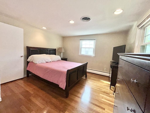 bedroom featuring recessed lighting, a baseboard heating unit, visible vents, and light wood finished floors