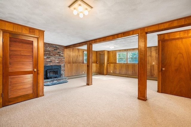 unfurnished living room with wood walls, a textured ceiling, a wood stove, and carpet floors