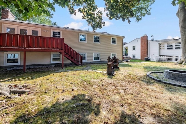 rear view of house with a yard, a fire pit, and stairs