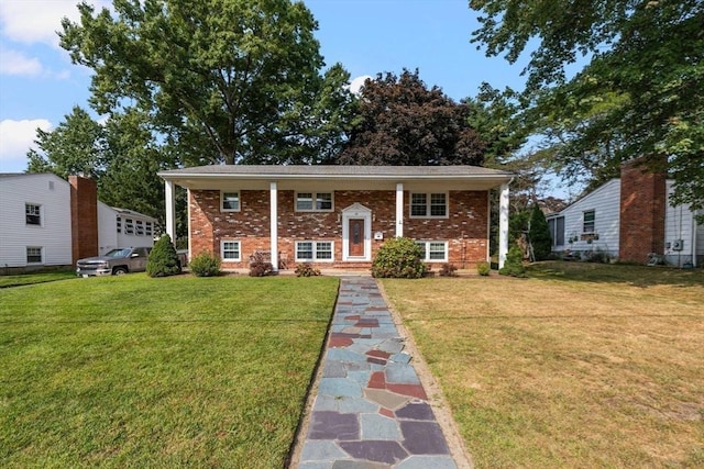 raised ranch featuring brick siding and a front yard