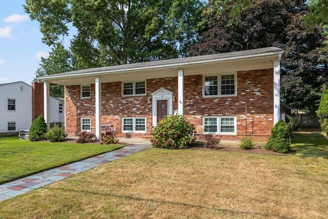 raised ranch with a front lawn and brick siding