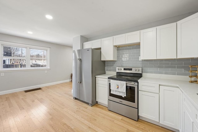 kitchen with decorative backsplash, light hardwood / wood-style floors, white cabinets, and appliances with stainless steel finishes