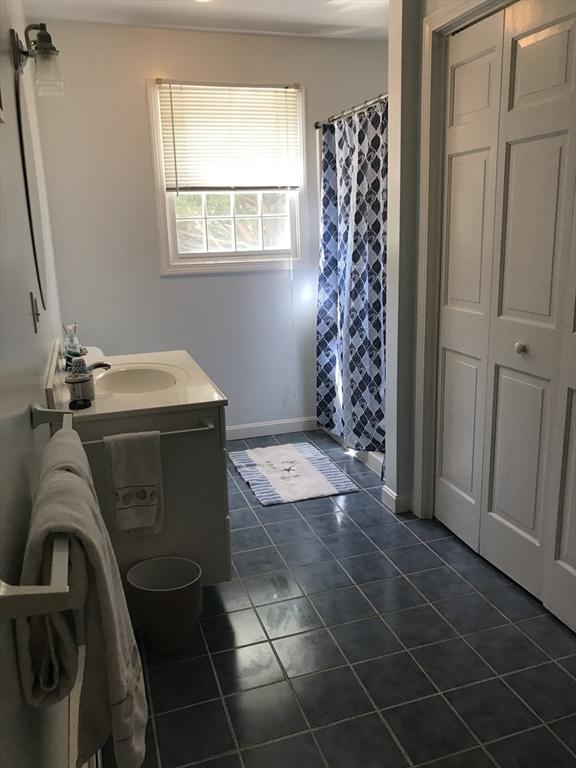 bathroom featuring curtained shower, tile patterned flooring, vanity, and baseboards