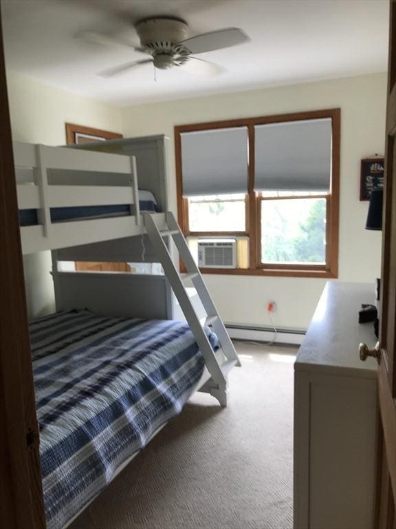 carpeted bedroom with a baseboard heating unit, ceiling fan, and cooling unit