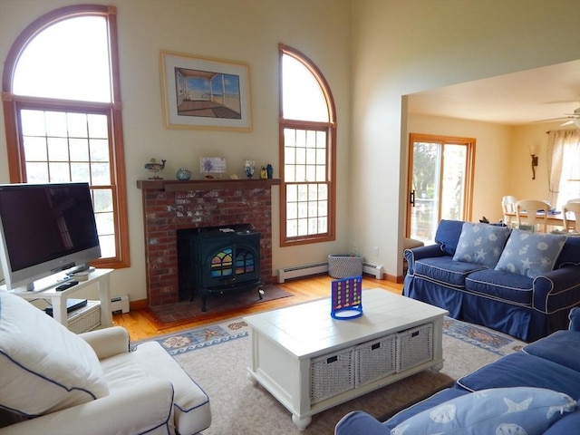 living area featuring a baseboard heating unit, a baseboard radiator, a ceiling fan, and light wood-style floors