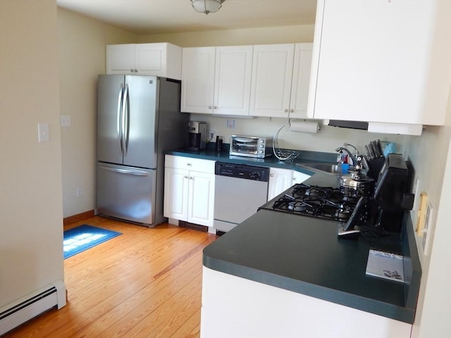 kitchen with dark countertops, a baseboard radiator, dishwasher, and freestanding refrigerator