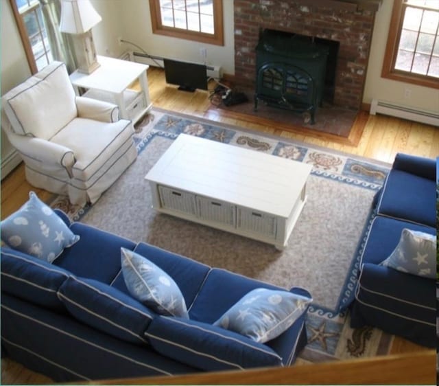 living room featuring a wood stove, a baseboard radiator, and wood finished floors