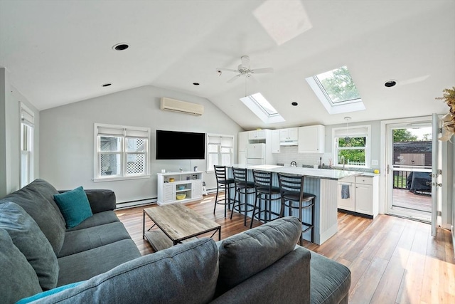 44 Macarthur Ln, Marshfield, MA 02050 - living room featuring a skylight, a wall mounted AC, a baseboard heating unit, light wood-type flooring, and vaulted ceiling