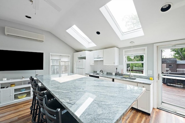 44 Macarthur Ln, Marshfield, MA 02050 - kitchen featuring a wall mounted air conditioner, a sink, white appliances, a skylight, and vaulted ceiling