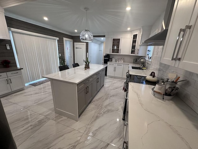 kitchen with crown molding, a center island, white cabinets, and decorative light fixtures