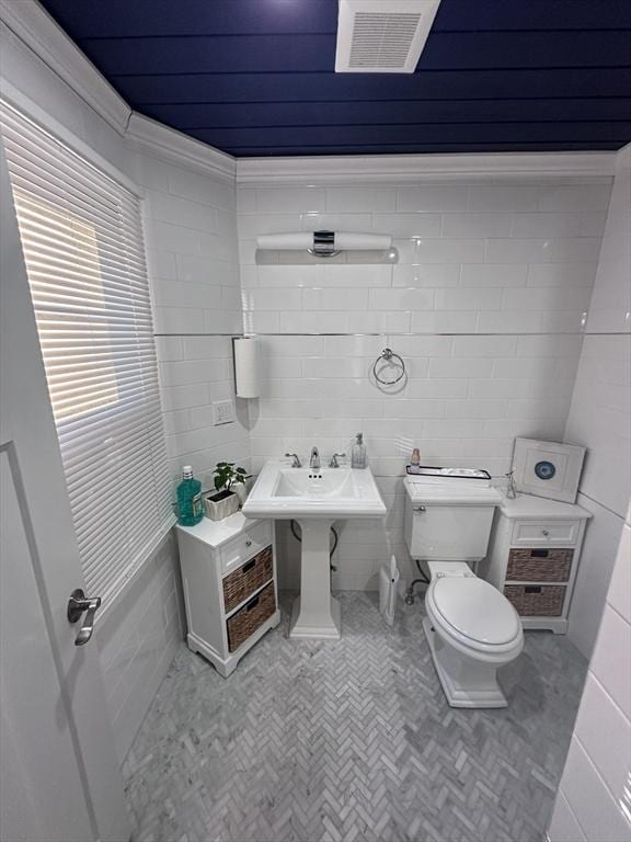 bathroom featuring toilet and tile walls