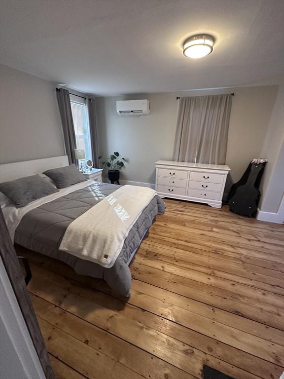 bedroom featuring light hardwood / wood-style flooring and a wall mounted air conditioner