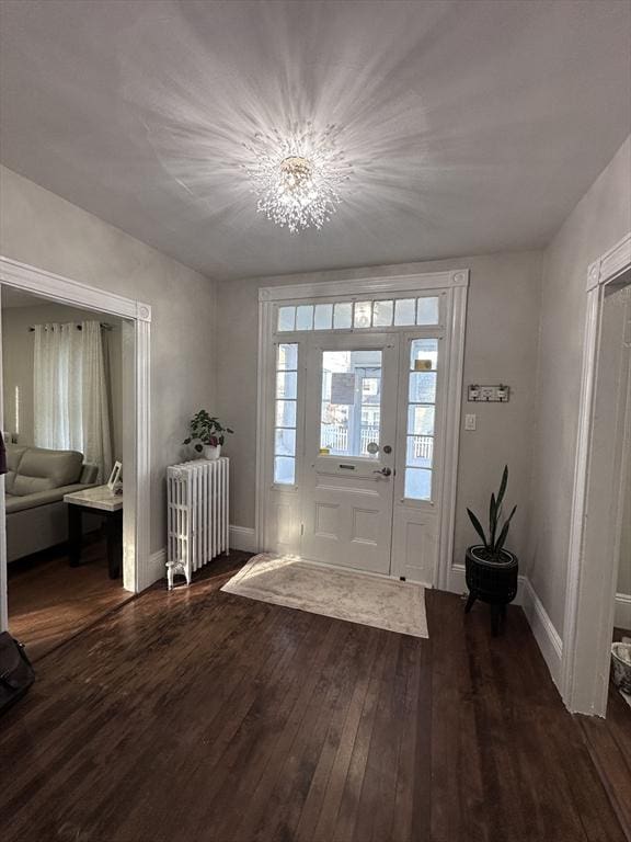 entrance foyer featuring dark hardwood / wood-style flooring, radiator, and a notable chandelier