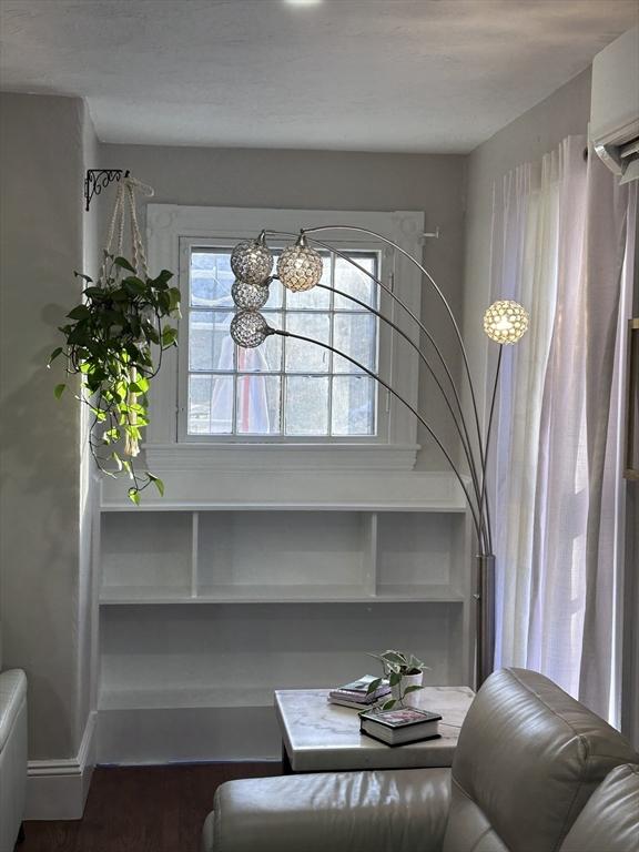 sitting room featuring hardwood / wood-style flooring and a wall mounted AC