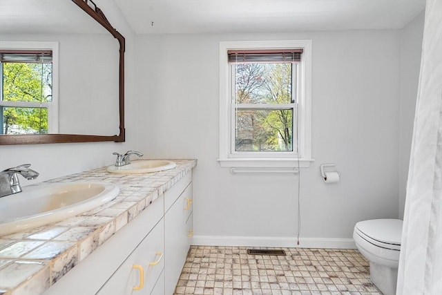 bathroom featuring toilet, baseboards, a sink, and tile patterned floors