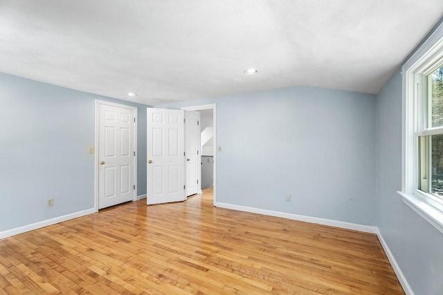 spare room featuring recessed lighting, baseboards, lofted ceiling, and light wood-type flooring