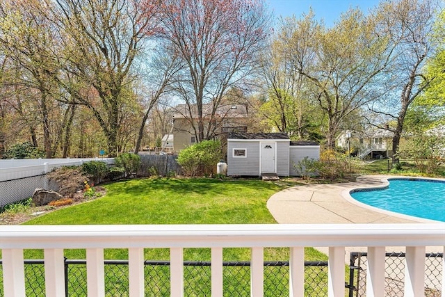 view of pool featuring a lawn, a fenced backyard, an outbuilding, and a storage shed