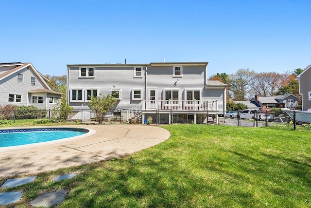 rear view of house with a fenced backyard, a fenced in pool, a wooden deck, and a yard