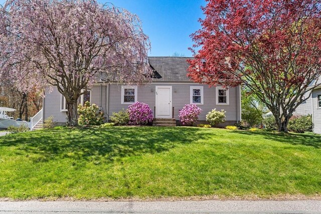 cape cod-style house featuring entry steps and a front yard