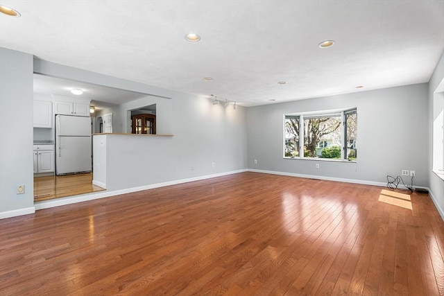 unfurnished living room with baseboards, recessed lighting, and hardwood / wood-style flooring