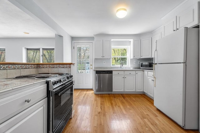 kitchen featuring a sink, appliances with stainless steel finishes, white cabinets, and light countertops
