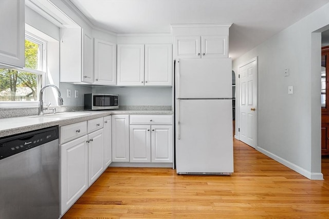 kitchen with a sink, appliances with stainless steel finishes, white cabinetry, and light countertops