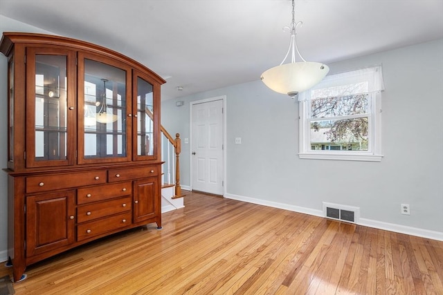 dining room featuring stairs, baseboards, visible vents, and light wood-style floors