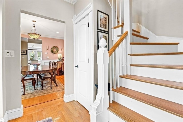 stairs featuring crown molding and wood-type flooring