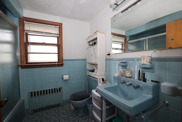 full bathroom with toilet, radiator, tile walls, and a wealth of natural light