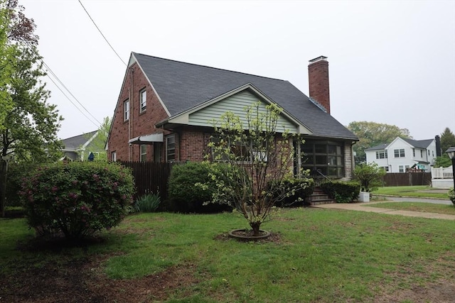 view of front of property with a chimney, a front yard, brick siding, and fence
