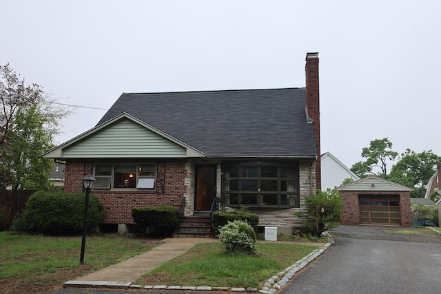 view of front facade with roof with shingles, a chimney, a garage, and aphalt driveway